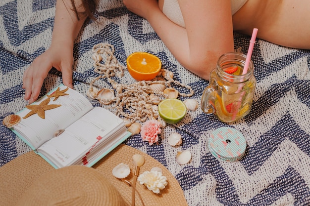 Foto gratuita chica con agenda y bebida en la playa