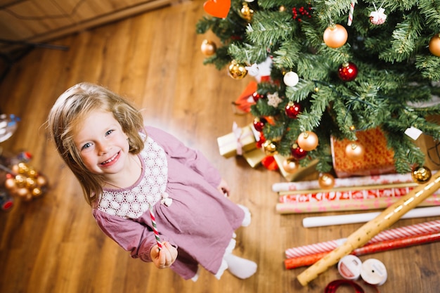 Chica al lado de árbol de navidad