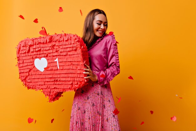 Chica alegre con bonita sonrisa posando con bunner rojo. refinada bloguera morena de buen humor.