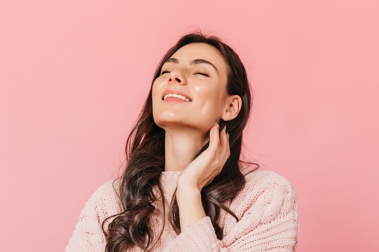 Foto gratuito chica alegre con cabello oscuro ondulado posa con sonrisa y ojos cerrados sobre fondo aislado.