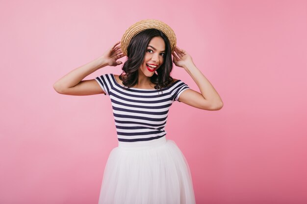 Chica alegre en camiseta a rayas posando con expresión divertida. Retrato de interior de mujer caucásica alegre con cabello castaño bailando.