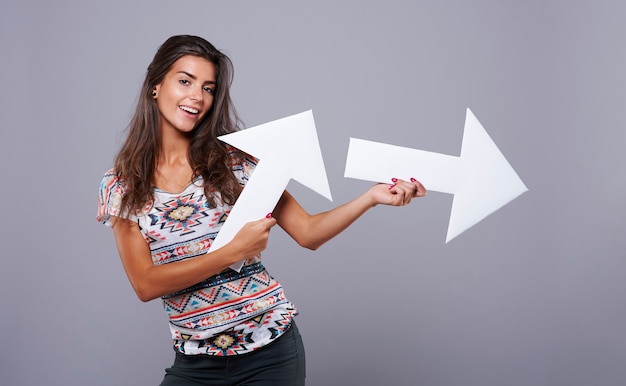 Chica alegre con carteles de flechas verticales y horizontales