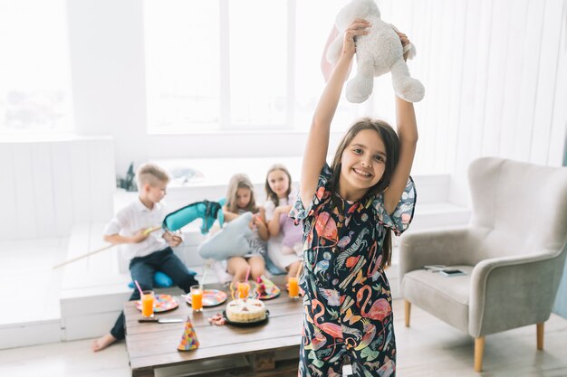 Chica alegre con conejo de juguete en la fiesta de cumpleaños