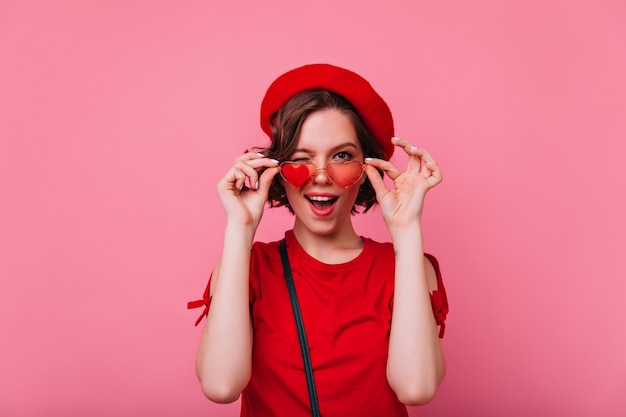 Chica alegre divirtiéndose dedicada al día de San Valentín. Foto interior de mujer francesa rizada divertida.