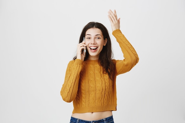 Chica alegre y feliz recibe buenas noticias durante la conversación telefónica