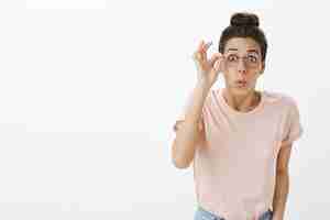 Foto gratuita chica alegre con gafas posando contra la pared blanca