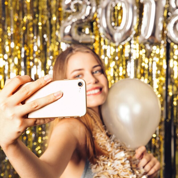 Chica alegre haciendo un selfie en fiesta de año nuevo