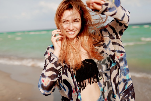 Foto gratuita chica alegre pelirroja posando en la playa soleada.