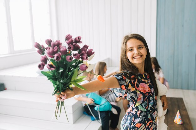 Chica alegre que muestra el ramo en la fiesta de cumpleaños