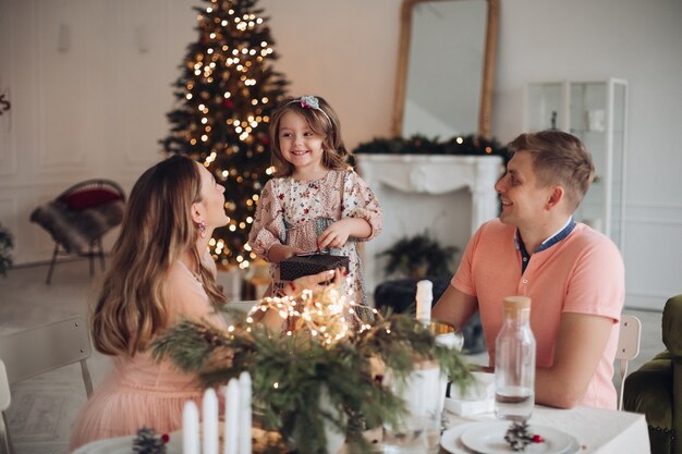 Chica alegre recibiendo regalos de Navidad de los padres