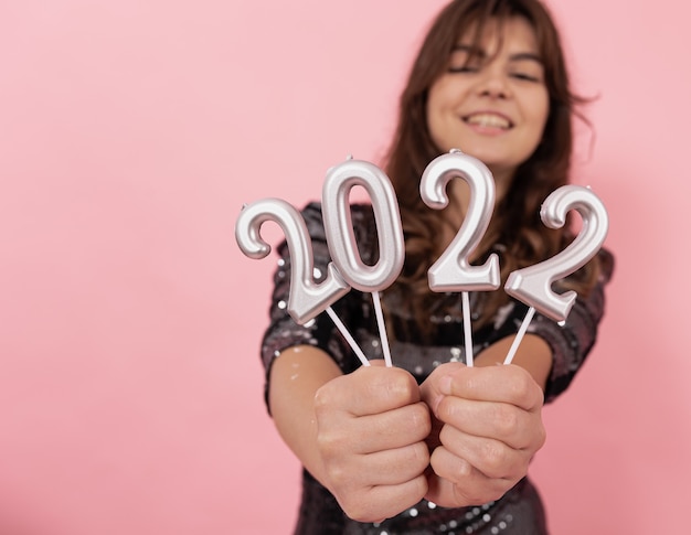 Foto gratuita una chica alegre sobre un fondo rosa tiene los números en sus manos