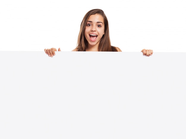 Chica alegre sujetando una cartel en blanco
