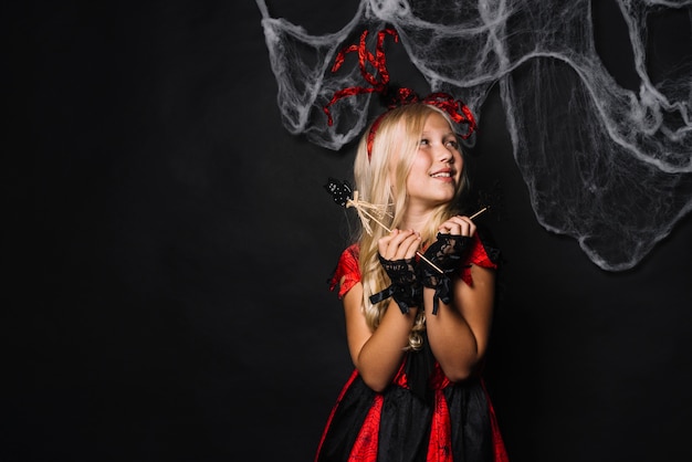 Chica alegre en traje rojo con juguetes de Halloween