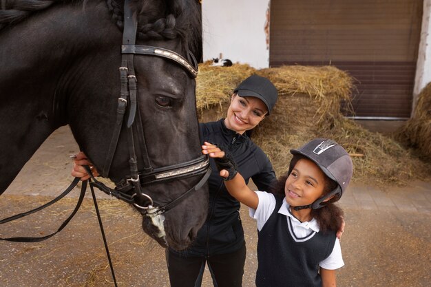 Chica de alto ángulo aprendiendo a montar a caballo