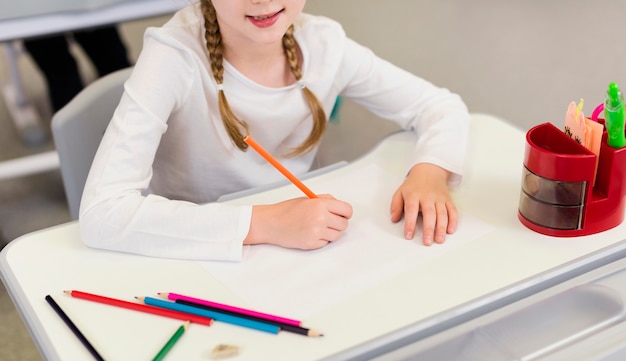 Chica de alto ángulo escribiendo en un cuaderno vacío