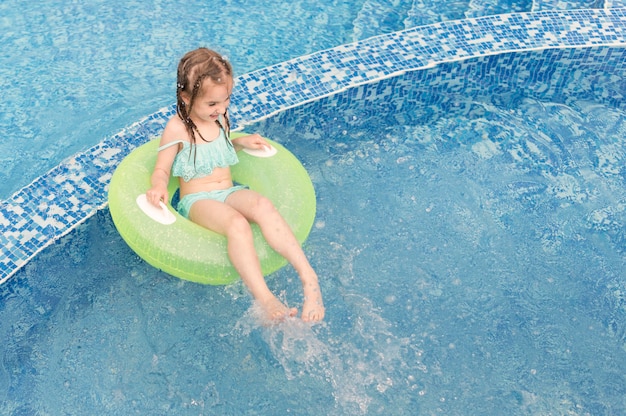 Chica de alto ángulo en flotador de piscina