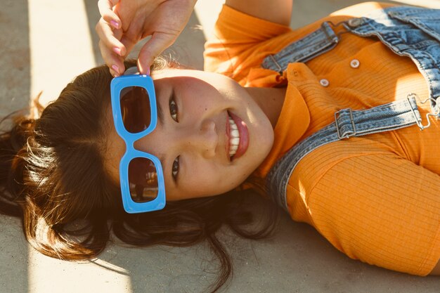 Chica de alto ángulo con gafas de sol azules