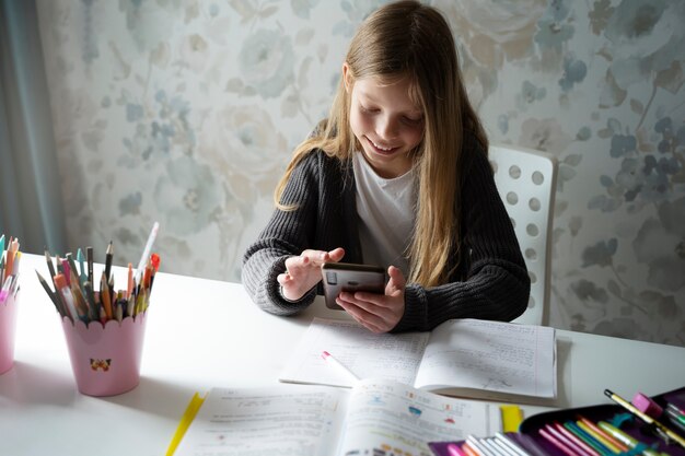 Chica de alto ángulo haciendo la tarea con el teléfono