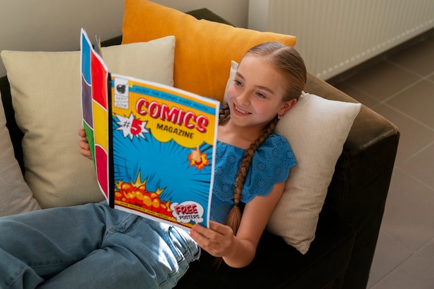 Foto gratuita chica de alto ángulo leyendo cómics en el interior