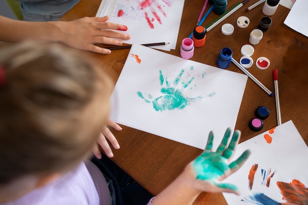 Foto gratuita chica de alto ángulo pintando con palma