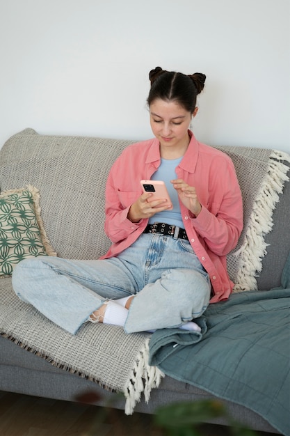 Chica de alto ángulo en el sofá con teléfono inteligente