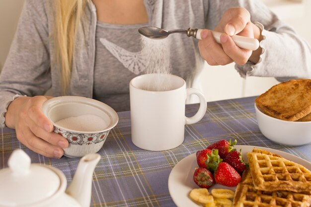 Chica añadiendo azúcar al té