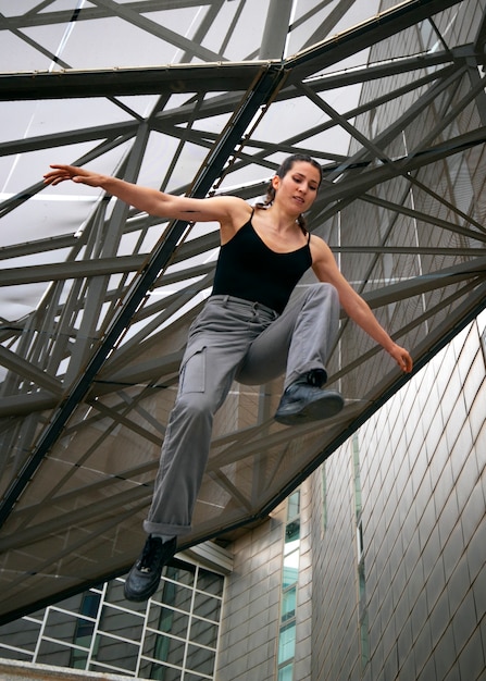 Foto gratuita chica de ángulo bajo haciendo entrenamiento de parkour