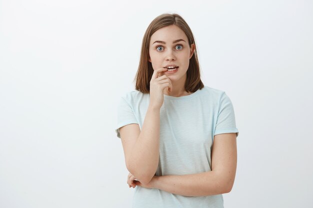 Chica ansiosa por conocer el final de la historia muriendo de emoción e interés. Retrato de curiosa mujer de buen aspecto, entusiasta y emocionada, ventilador de la serie de televisión mordiendo la uña y mirando enfocado