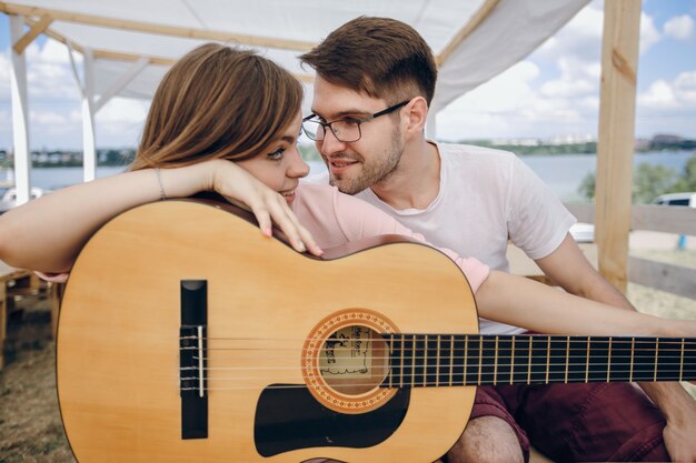 Chica apoyada en una guitarra mirando a su novio