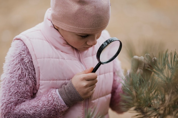 Chica aprendiendo ciencias en la naturaleza con una lupa.