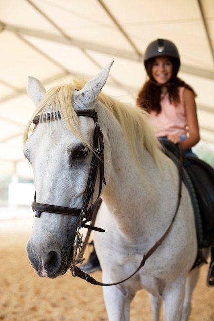 Foto gratuita chica aprendiendo a montar a caballo