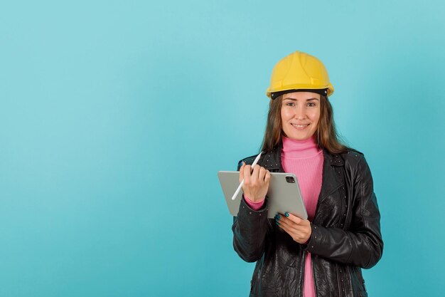 Chica arquitecta con tablet planshet está sonriendo sobre fondo azul.