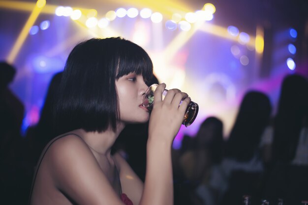 chica asiática bebiendo cerveza en un bar