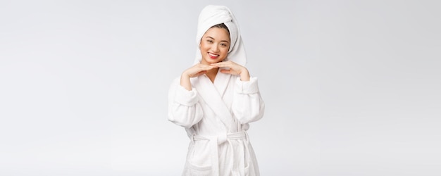 Chica asiática de belleza que comprueba su cuidado de la piel de la piel aislado sobre fondo blanco.