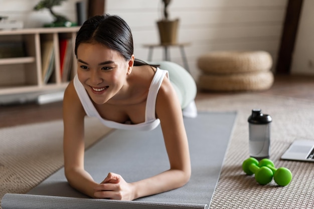 Foto gratuita chica asiática deportiva en ropa deportiva haciendo ejercicio en casa sigue la guía de video ...