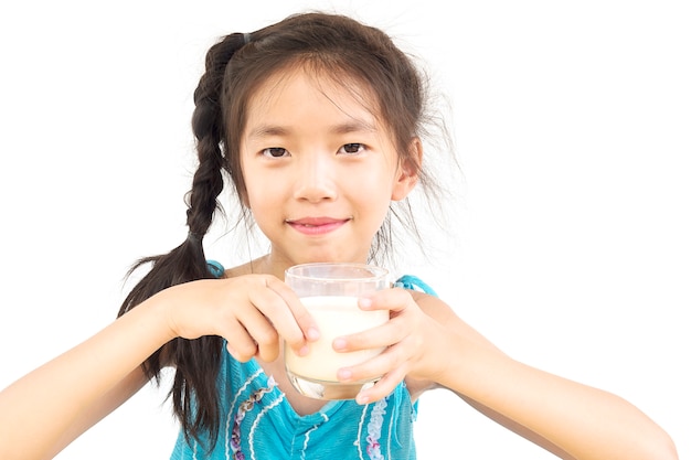 Chica asiática está bebiendo un vaso de leche sobre fondo blanco