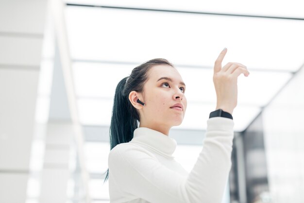 Chica asiática tocando la tecnología futurista de pantalla virtual