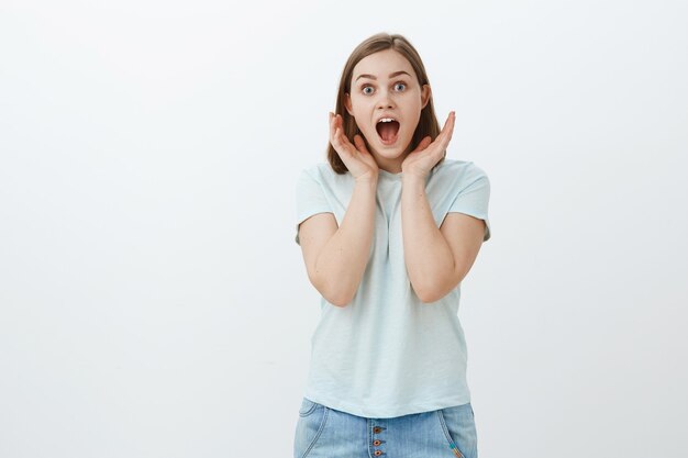 La chica asombrada y divertida no puede creer lo que oye. Retrato de mujer europea entusiasta sorprendida asombrada en camiseta de moda gritando de alegría y asombro sosteniendo las palmas cerca de la cara mirando