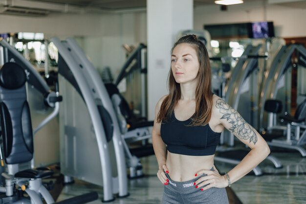 Chica atlética atractiva se encuentra en la pared de simuladores en el gimnasio. estilo de vida saludable.