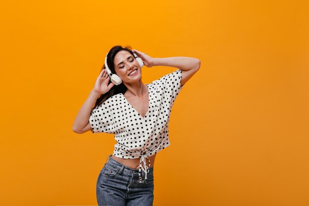 Chica atractiva en camiseta de lunares escucha música en auriculares