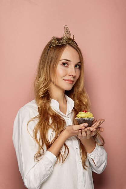 Chica atractiva con una corona y cupcake