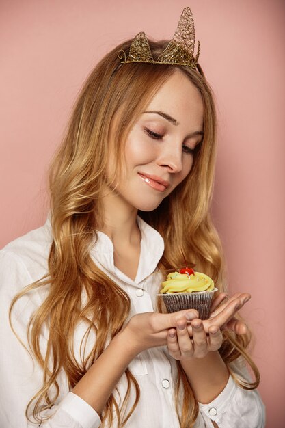 Chica atractiva con una corona y cupcake