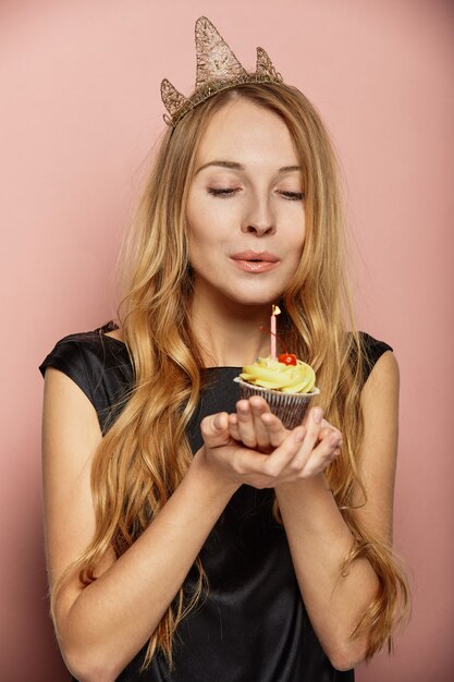 Chica atractiva con una corona y cupcake