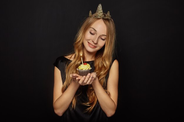 Chica atractiva con una corona y cupcake