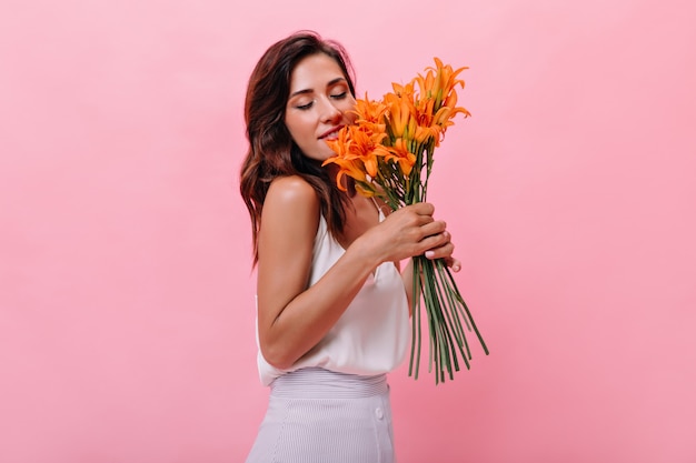 Foto gratuita chica atractiva disfruta de aroma de flores sobre fondo aislado