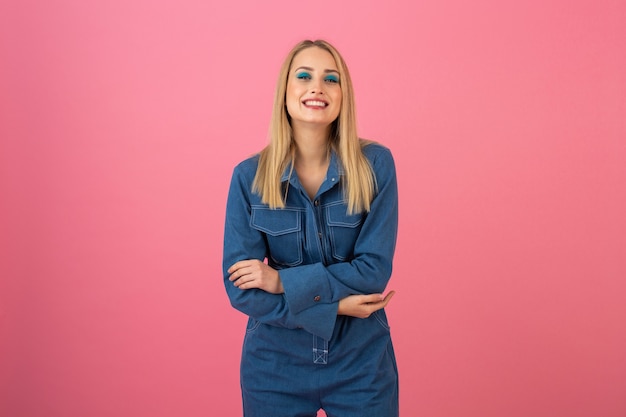 Chica atractiva emocionada posando sobre fondo rosa en tendencia de moda general de mezclilla