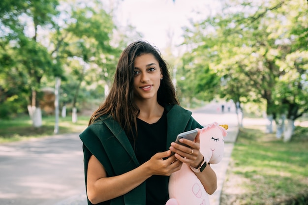 Chica atractiva joven escribiendo mensajes en su móvil.