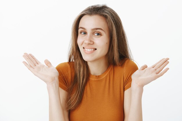 Chica atractiva rubia sorprendida feliz levantando las manos y sonriendo