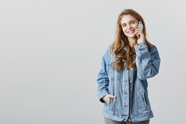 Chica atractiva sonriente hablando por teléfono con cara feliz