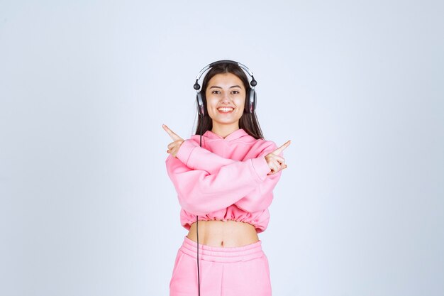 Chica con auriculares y apuntando hacia el lado derecho. Foto de alta calidad